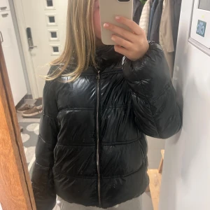 Svart/blå pufferjacka från Massimo Dutti - Säljer en svart pufferjacka från Massimo Dutti med glansig finish. Jackan har hög krage, två fickor med dragkedja och ”quiltad” design. Den är i mycket bra kvalitet! 💞