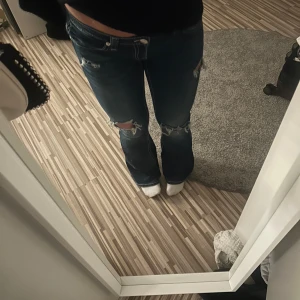 Blå bootcut jeans med hål  - Snygga blå jeans med bootcut passform och slitna detaljer på knäna. Jeansen har låg midja och broderat tryck på bakfickorna. Hålen är lite uppslitna men jeansen är använda max 3 gånger💗Jeansen är i barnstorlek men passar mig som brukar ha strl 36 i byxor:)