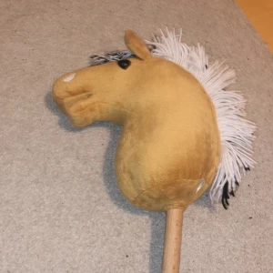 Käpphäst(fjording) - Denna produkt är en klassisk leksakshäst på pinne, med mjukt brunt/becht tyg och vit/svart man. Hästen har ett vänligt uttryck och är perfekt för käpphästhoppning, ridtur i skogen eller något annat! Tveka inte om det är nåt!Hör av dig till mig!