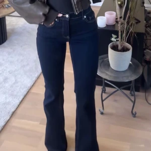 Mörkblå bootcut jeans - Snygga mörkblå jeans med bootcut passform och klassiska kontrastsömmar. Byxorna har hög midja och är tillverkade i ett stretchigt denim-material som sitter bekvämt. Perfekta för dig som gillar en tidlös och trendig look.