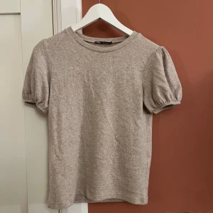 Beige puffärm topp från Zara - Säljer en beige topp från Zara med puffiga korta ärmar och rund halsringning. Enkel design utan mönster eller detaljer. Den är i storlek M men passar S. Pris kan diskuteras💗