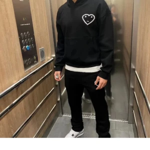 Svart hoodie Carsicko - Svart hoodie Carsicko. Klassisk huva och magficka framtill. Tröjan har långärmad passform och är perfekt för dig som gillar stilrena streetwear-plagg med en twist. Snygg att matcha med jeans eller joggers.