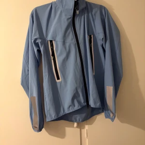 Ljusblå vindjacka från CRW - Snygg ljusblå vindjacka från CRW med svarta dragkedjor och vita detaljer.  Storlek M💙 aldrig använd.