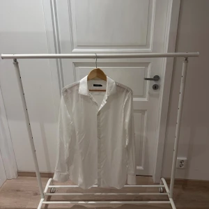 Vit skjorta från J.Lindeberg - Klassisk vit skjorta från J.Lindeberg i 100% bomull, modell Daniel CA TL Non-iron Oxford. Skjortan har lång ärm, knappar framtill och en stilren krage. Perfekt för dig som gillar enkel och clean stil med snygg passform.