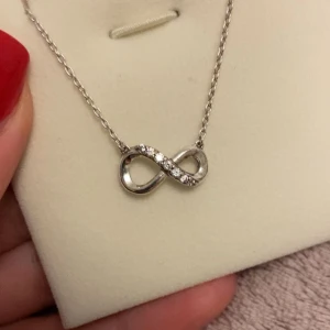 Pandora halsband i silver - Snyggt halsband från Pandora i äkta sterlingsilver med en glittrande evighetssymbol dekorerad med små klara stenar. Märkt med S925 ALE. Använd 1-3 gånger, kommer utan förpackning.