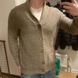 Beige stickad cardigan - Skit fet beige stickad cardigan i storlek M. Modellen är 180cm, 73kg. Priset går att diskutera!