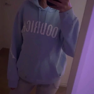 Ljusblå hoodie från hoodrich  - Säljer en ljusblå hoodie med vit text framtill och på ryggen. Tröjan har luva med snörning och långa ärmar, perfekt för chill dagar.billigare vid snabb affär 
