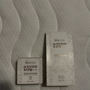 IDC Institute Scented Bath Bronze - Lyxigt set med tvål och badsalt från IDC Institute i serien Scented Bath Bronze. Doft av apelsin och cederträ. Förpackningarna är ljusbeige med guldmönster och text. Tvålen är 100g och badsaltet 150g, perfekt för en fräsch och väldoftande stund.