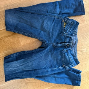 Levi's 501 blå jeans straight fit - Säljer ett par klassiska Levi's 501 jeans i mörkblå tvätt med raka ben och fem fickor. Jeansen har knappgylf och tydliga Levi's-detaljer på bakfickorna. Perfekt för dig som gillar tidlös och avslappnad stil.