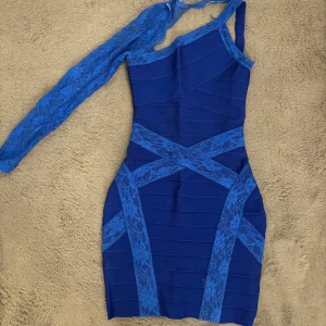 Blå oneshoulder klänning med spets - Snygg blå kortklänning med asymmetrisk design och en lång spetsärm. Klänningen har tight passform och är dekorerad med blommig spets. Sitter så fint på kroppen och passar vid olika tillfällen. Skriv för fler bilder🥰