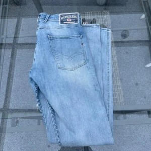 🩵 Replay Blue Jeans – Ljusblå denim i klassisk stil - Snygga ljusblå jeans från Replay Blue Jeans, i högkvalitativ denim med perfekt passform. Klassisk femficksmodell med diskreta slitningar och ikonisk Replay-logga bak. Jeansen är mjuka, bekväma och sitter riktigt snyggt både till vardag och fest.  ✅ Äkta Replay ✅ Mjukt stretchigt denim ✅ Ljus tvätt – perfekt till vår och sommar ✅ Stilrena detaljer & bra kvalitet  📏 Storlek: W32/L32 📦 Skick: bra skick – använda