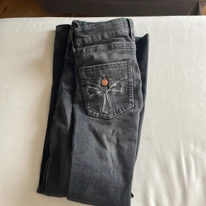 Svarta jeans från Gina Tricot, strl 170 - Snygga svarta jeans från Gina Tricot i storlek 170. Jeansen har en cool bakficka med broderad detalj och knapp, klassisk femficksmodell och raka ben. Materialet är jeans och färgen är mörkgrå/svart med lätt tvättad look.