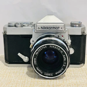 Nikon Kamera - Klassisk Nikkormat FT analog systemkamera från Nikon med Nikkor-H Auto 50mm f/2 objektiv. Kameran är i gott skick med mindre yttre slitage, alla reglage och slutare ser ut att fungera. Perfekt för filmfotoentusiaster och samlare. Tillverkad i Japan. 