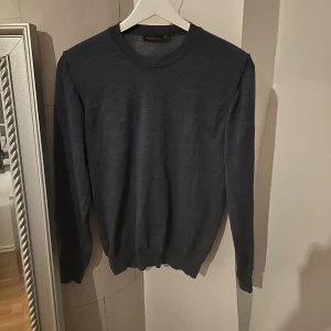  rundhalsad tröja Oscar Jacobson blå - En rundhalsad tröja från Oscar Jacobson i en lite starke och ljusare blå färg. Denna tröja är i merino ull och är lite tunnare. Den har en slimmad passform och är i modellen Miguel denim blue. Köpt på NK Göteborg och ny pris är 1500kr har kvitto om det önskas se. Hör av dig vid minsta lilla