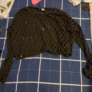 Grön  croppad topp från H&M Divided - Säljer en grön croppad topp från H&M Divided med lång ärm och coolt hålmönster över hela plagget. 