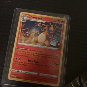 Charizard - Snygg Charizard Pokémon-kort i plastfodral! Perfekt för dig som samlar eller vill boosta din lek med en av de mest ikoniska och kraftfulla drakarna. Kortet har coolt motiv och specialförmågor som Battle Sense och Royal Blaze. Ett måste för alla Pokémon-fans!