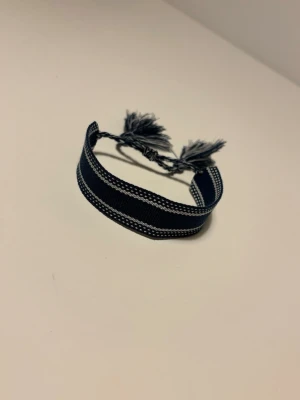 Dior liknande armband - Snyggt mörkblått armband i tyg som liknar ett Christian Dior armand . Armbandet har en bred design och passar perfekt för dig som gillar en avslappnad.