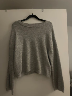 Grå stickad tröja med lös passform - Mysig grå stickad tröja med bred rund halsringning och långa ärmar. Den är i storlek XL men passar mer som en M. 