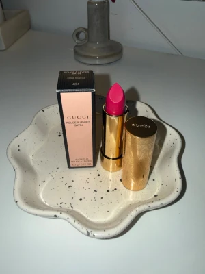 Gucci Rouge à Lèvres Satin 404 - Gucci Rouge à Lèvres Satin – 404 Cassie Magenta (NY)  Säljer ett helt nytt och oanvänt läppstift från Gucci. Modell: Rouge à Lèvres Satin Nyans: 404 Cassie Magenta  Endast öppnad för bild, aldrig testad på läppar. Kommer med originalförpackning (se bilder).  Nypris i butik: ca 550 kr