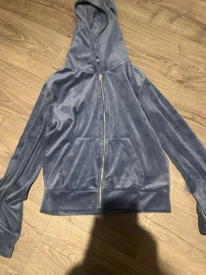 Blå velourhoodie från 151 - Mjuk och skön blå velourhoodie från 151 med dragkedja framtill och stor känguruficka. Hoodien har en avslappnad passform och huva, perfekt för chill dagar. Materialet är lent och ger en lyxig känsla.