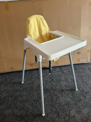 Vit barnmatstol med gul dyna - Säljer en enkel och praktisk barnmatstol i vit plast med grå metallben. Stolen har en avtagbar gul dyna och ett stort brickbord framtill. Perfekt för småbarn vid matbordet och lätt att rengöra.