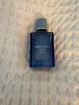 Jimmy Choo Man Aqua parfym - Fräsch herrparfym från Jimmy Choo, Man Aqua. Flaskan är rektangulär i blått glas med silverfärgad och mönstrad kork. Perfekt för dig som gillar en modern och stilren doft.