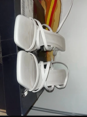 Vita sandaler med remmar och klack - Säljer ett par stilrena vita pumps med remmar och fyrkantig tå. Endast använda 2 gånger