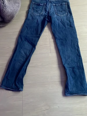 Blå Replay jeans straight fit - Säljer ett par klassiska blå jeans från Replay med raka ben och normal passform. Jeansen har två bakfickor med snygga sömmar och Replay-lapp i midjan. Tillverkade i slitstarkt denimtyg av bomull. Perfekta för dig som gillar tidlös stil.