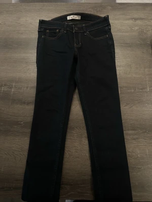 Mörkblå hollister jeans straight fit - Snygga mörkblå hollister jeans med klassiska kontrastsömmar och raka ben. Jeansen har fem fickor och är tillverkade i slitstarkt bomullsjeansmaterial. Perfekta för dig som gillar en clean och tidlös look.