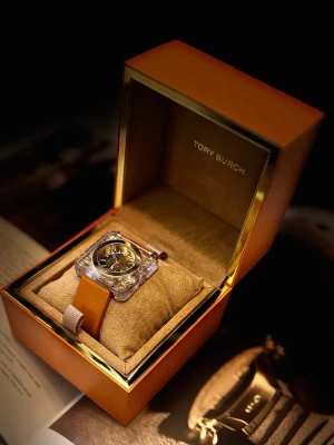 Tory Burch fyrkantig klocka i guld - Snygg klocka från Tory Burch med fyrkantigt guldigt ur och brunt läderarmband. Kommer i original orange ask med logga och medföljande dokumentation. Perfekt accessoar för dig som gillar stilrena detaljer och lyxig känsla.