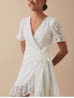 Studentklänning - Söt vit kort omlottklänning från Gina tricot i spets och knyt i midjan. Perfekt för studenten eller sommarens alla tillfällen! Köpt på plick men aldrig använd av mig, mycket fint skick