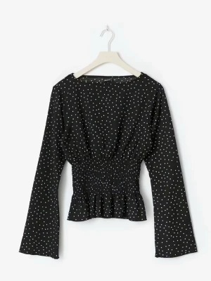 Svart prickig blus med smock - Trendig svart blus med vita prickar och smockad midja. Långa ärmar och lätt utsvängd nederkant ger en snygg siluett. Perfekt att styla med jeans eller kjol för en cool look.