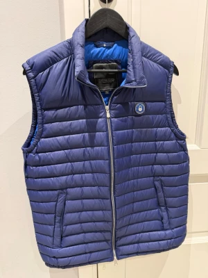 Blå Sail Racing väst - Snygg dunväst i marinblå ifrån Sail Racing. De är herr i storlek L. Västen är endast använd fåtal gånger så är mycket bra skick! 