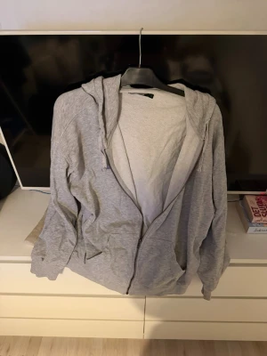 Grå zip hoodie med huva från bikbok - Enkel och stilren grå hoodie med dragkedja framtill och två fickor. Hoodien har justerbar huva med snören och är tillverkad i mjukt sweatshirtmaterial. Perfekt för chill dagar eller när du vill ha en avslappnad look. Storlek S men folk som bär M kan även använda denna då den är stor i storleken ordpris: 500kr säljer för 230kr plus frakt då jag har använt den max 5 gånger 
