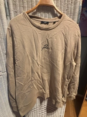 Beige sweatshirt  - Beige sweatshirt från Peak Performance med broderad logga på bröstet. Tröjan har rund halsringning och långa ärmar. Tillverkad i mjukt material som känns skönt mot huden. Perfekt för en avslappnad och stilren look.