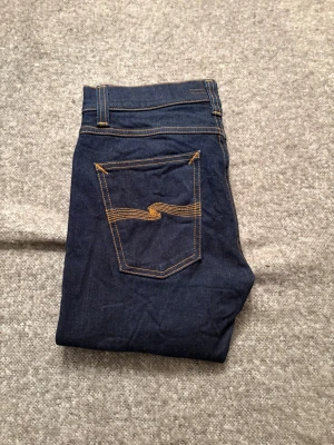 Mörkblå skinny jeans från Nudie - Säljer ett par mörkblå jeans från Nudie med klassisk orange söm och fem fickor, kom dm vid frågor✅