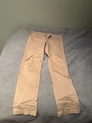 Beige chinos från Uniqlo 33x34 - Säljer ett par riktigt snygga beige chinos från Uniqlo i storlek 33x34. Väldigt bra skick, skrynkliga endast pga nedvikta. Mitt pris är endast 299. Hör av dig vid frågor!! 