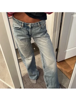 Ljusblåa baggy/straight jeans - Säljer ett par ljusblåa monki jeans med loose fit och låg midja. Jeansen har klassisk femficksdesign, raka ben och är tillverkade i slitstarkt denim. Perfekta för en avslappnad och trendig look.