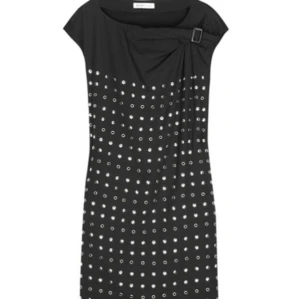 Svart kortklänning See by Chloé - Supersnygg svart kortklänning från See by Chloé med coola silvriga nitar i mönster över hela klänningen. Asymmetrisk drapering vid axeln med dekorativt spänne. Ärmlös modell i mjukt material, perfekt för dig som vill sticka ut.