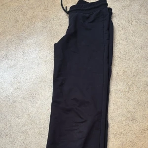 Svarta utsvängda byxor  - Svarta utsvängda byxor från bikbok med elastisk midja och dragsko. Byxorna har en rak passform och är tillverkade i ett mjukt bomullsmaterial som är skönt att ha på sig.