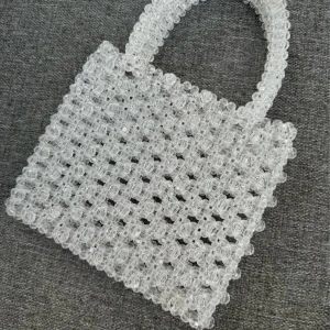 Transparent pärlhandväska med handtag - Superfin handväska gjord av transparenta pärlor i fyrkantig form. Väskan har ett stadigt handtag och ett utseende som verkligen sticker ut. Perfekt accessoar för att lyfta din outfit med en fin touch.