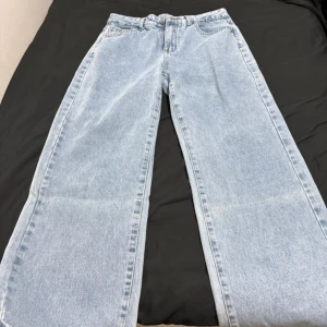 Ljusblå wide jeans med raka ben - Säljer ett par ljusblå jeans med bred passform och raka ben. Jeansen har klassisk femficksdesign och stängs med knapp och dragkedja. Perfekta för dig som gillar en avslappnad och trendig stil.  Storlek M,passar i L