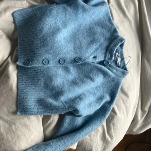 Blå kofta från Zara med knappar - Mysig blå kofta från Zara med stora matchande knappar framtill. Koftan är stickad och har ribbade muddar vid ärmslut och nederkant. Perfekt för lager-på-lager och chill dagar. Enkel och stilren design som funkar till det mesta.