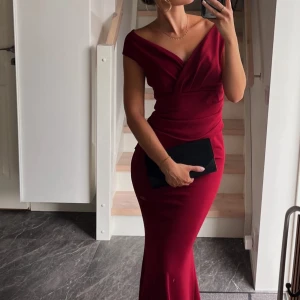 Balklänning vinröd  - Säljer en elegant vinröd långklänning från Goddiva / bubbleroom med v-ringad omlott överdel och figurnära passform. Klänningen har offshoulder-skärning och är tillverkad i ett mjukt, stretchigt material som ger en snygg siluett. Perfekt för bal eller festliga tillfällen. Använd endast 1 gång så den är i mycket bra skick, super fin! 