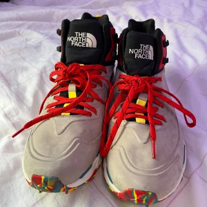 The North Face Vectiv Futurelight sneakers - Snygga The North Face Vectiv Futurelight sneakers med grå ovandel, svarta detaljer och röda snören. Skorna har färgglad sula i rött, gult och blått, samt gula och röda accenter. Perfekta för dig som vill sticka ut med både stil och funktion.