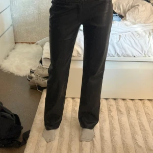 Svarta raka byxor i skinnimitation Nelly - Snygga svarta byxor från Nelly i skinnimitation med rak passform. Byxorna har klassisk midja och stilren look som passar till många olika outfits. Perfekta för dig som vill ha en edgy vibe i garderoben.