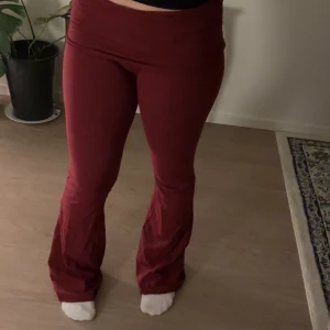 Vinröda bootcut byxor från RYVLS - Säljer ett par vinröda bootcut byxor från RYVLS i storlek 170/176. Byxorna har mid midja och är gjorda i ett stretchigt, mjukt material som sitter tajt upptill och släpper ut vid benen. Perfekta för dig som gillar en bekväm och snygg look.