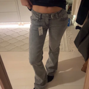 Grå bootcut jeans - Snygga grå jeans från lager 157 i bootcut-modell med två knappar i midjan och broderade detaljer på bakfickorna. Helt oanvända med lapparna kvar.