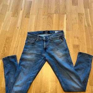 Replay Anbass blå jeans, stl 29/30 - Snygga Replay Anbass jeans i klassisk blå tvätt med lätt slitning. Modellen har fem fickor, dragkedjegylf och raka ben. Perfekta för dig som gillar en modern och stilren look. Materialet är mjukt och stretchigt för extra komfort. Pris kan diskuteras vid snabb affär 