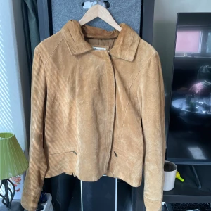 Beige mockajacka från Coldwater Creek - Snygg beige mockajacka från Coldwater Creek med klassisk krage och diskreta fickor med dragkedja. 100% mocka. Har några missfärgningar/smuts??